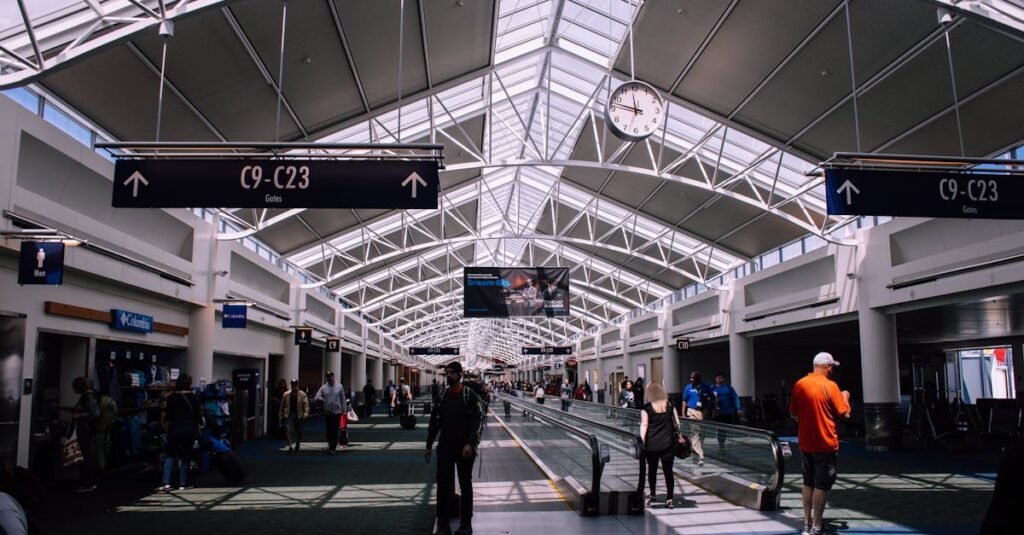 Spacious airport terminal with moving walkway and travelers, showcasing modern architecture.