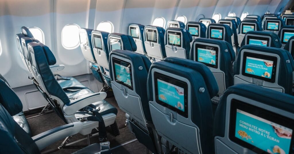 Empty airplane interior highlighting rows of seats with touchscreens, offering a modern in-flight experience.
