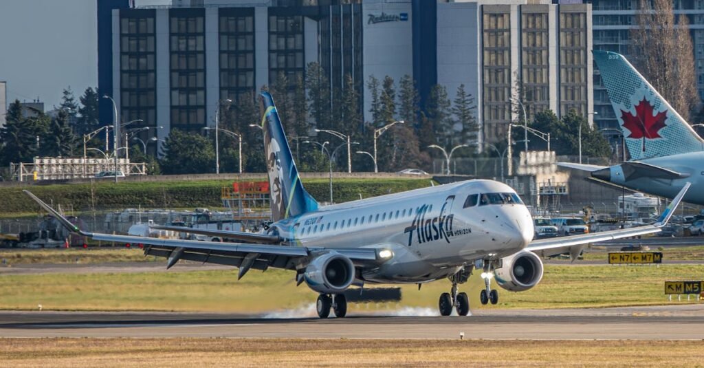 An Alaska Horizon airplane lands on a runway with buildings in the background, showcasing aviation and transportation.
