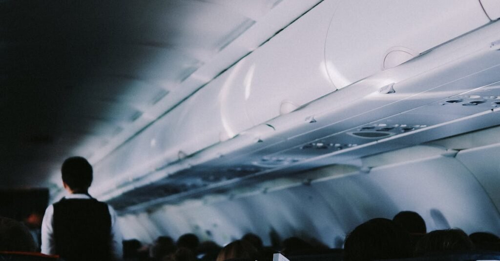 pexels-photo-20371169-20371169 Interior view of airplane cabin with passengers seated and flight attendant in aisle.