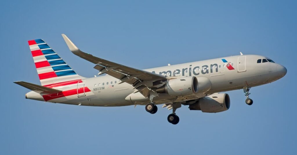American Airlines Airbus A319 airplane landing under clear sky in New York City.