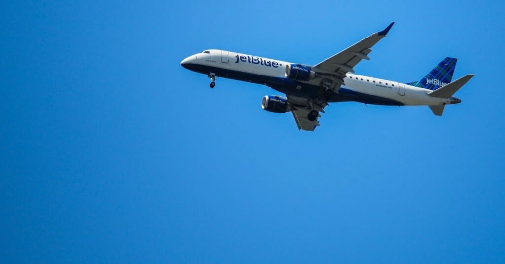 JetBlue airplane flying in clear blue skies, showcasing aviation in motion.