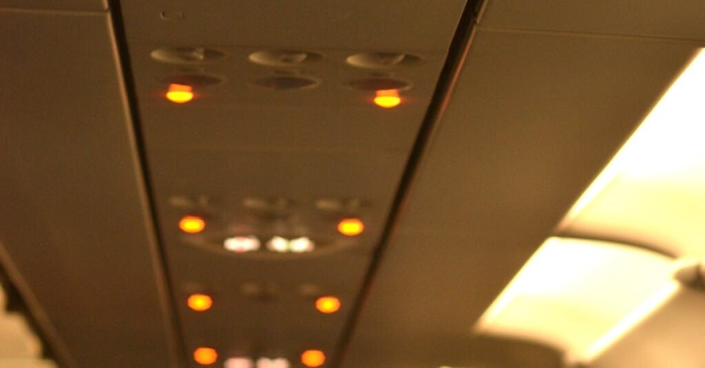 Interior of a well-lit airplane cabin showing the overhead safety signs and passenger seating.