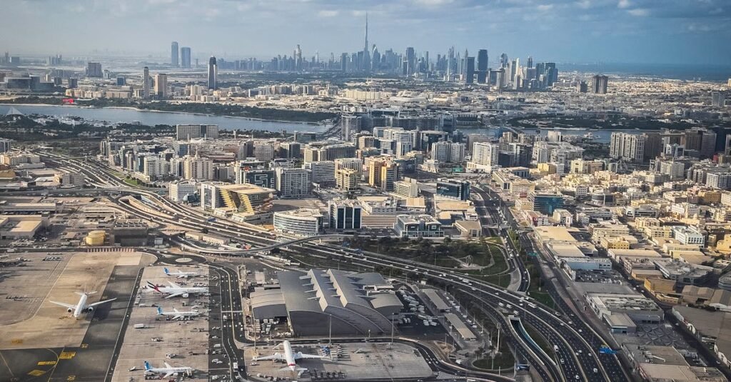 Stunning aerial view of Dubai cityscape with an airport in the foreground and skyscrapers in the distance.