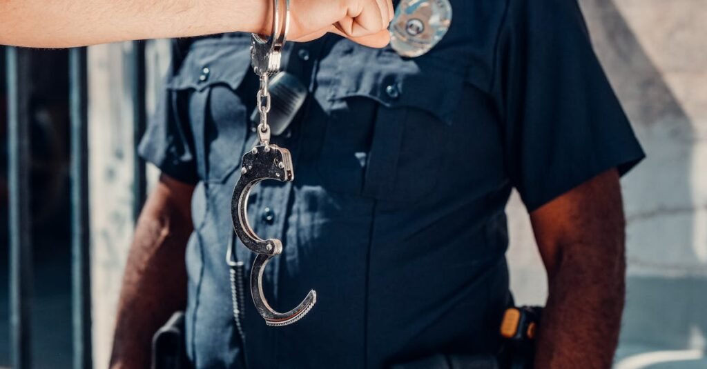 A police officer in uniform holds open handcuffs outdoors, clear authority symbol.