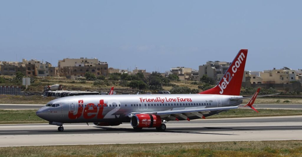 Jet2 airplane on the runway with buildings in the background on a sunny day.